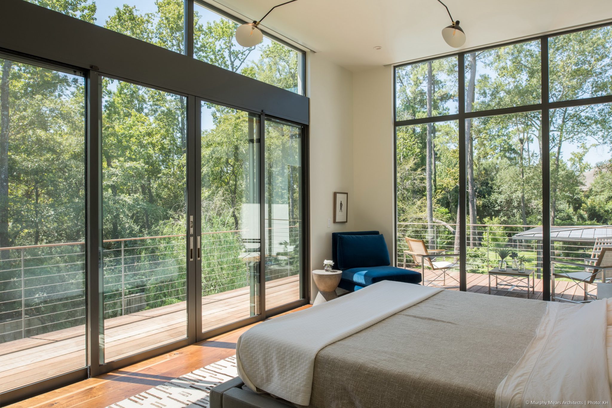 Carlton Woods Residence - Sliding glass doors open up to the wood and steel master balcony which overlooks the dense green backyard landscape.