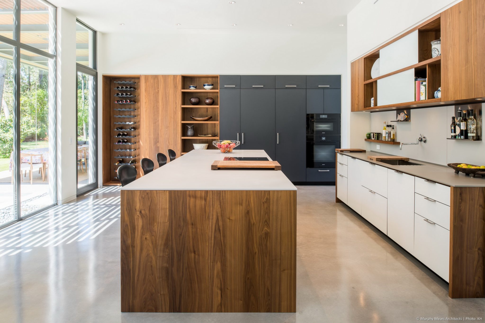 Carlton Woods Residence - A central island and two storage walls arranged for open flow through the kitchen and generous views of the backyard space.